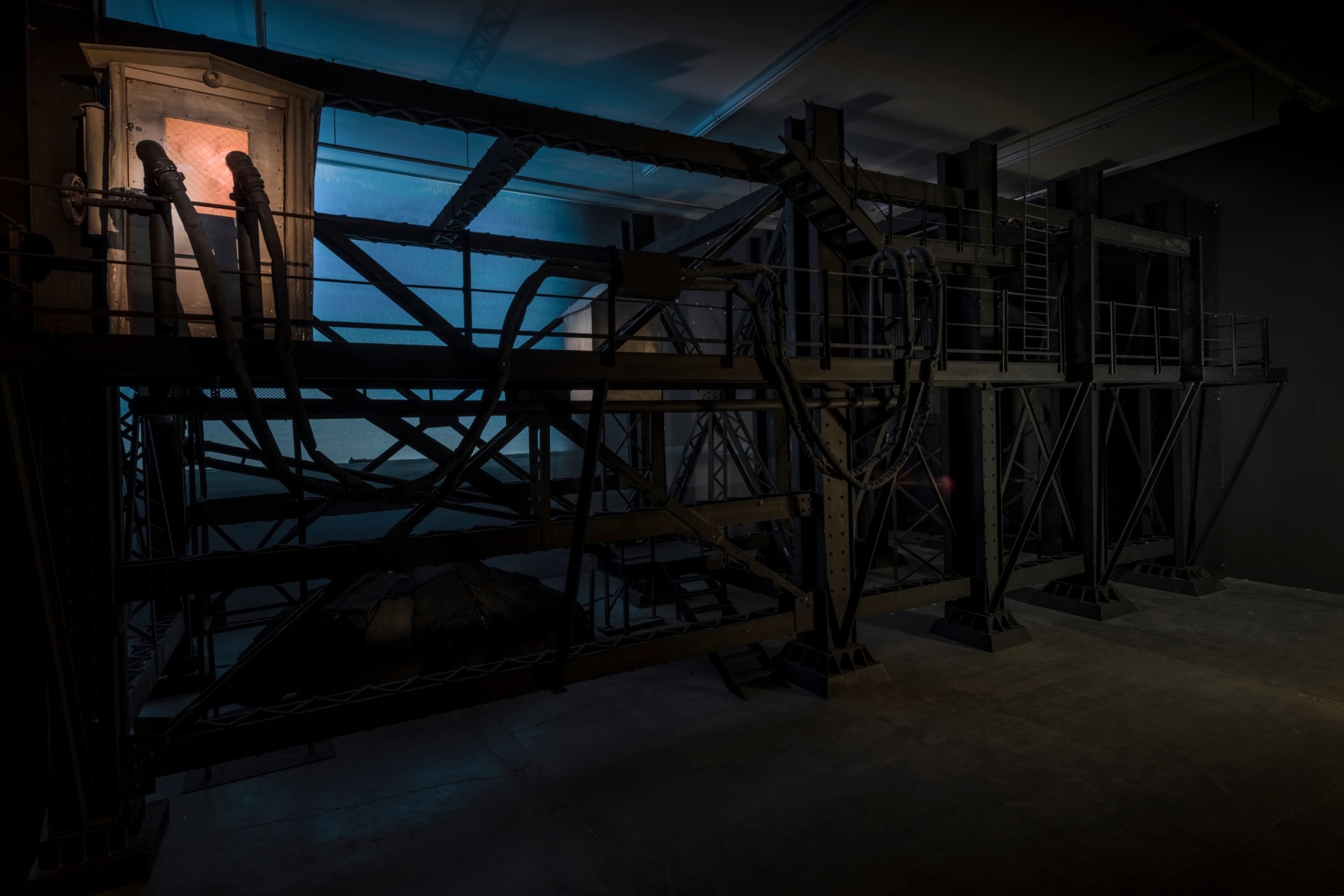 Ship/Dock/Three Houses and the Night Sky, 2023, Wood, plastic, glass, acrylic paint, electrical fixtures, metal, video projections, sound, darkness, 12’ x 29’9” x 14’9”