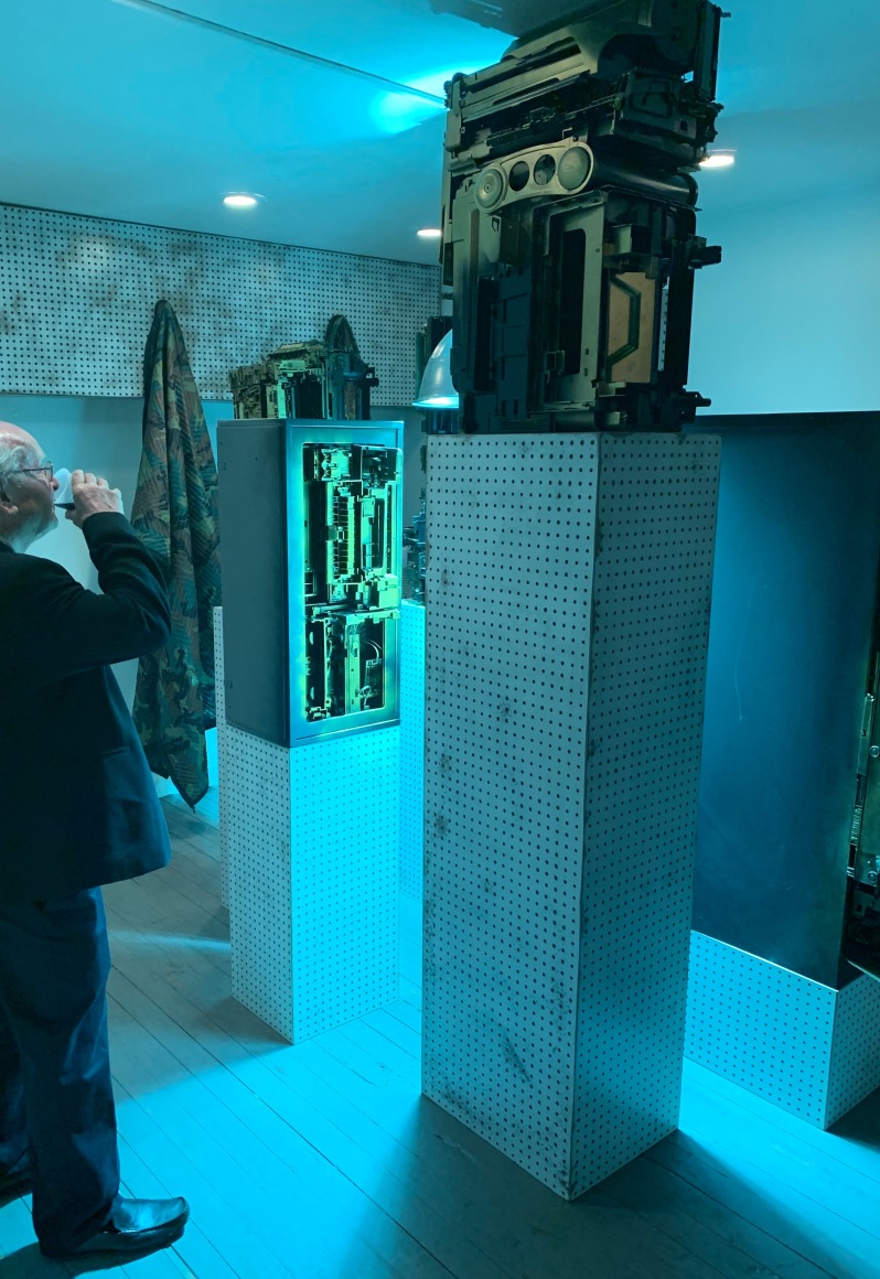 Upstairs exhibition room - Exhibiting five assemblage sculptures on pegboard pedestals- various sizes. Sculptures were placed surrounding a condensed 400-watt sulfur lamp, low hanging with a loud buzzing sound. Phil Wagner, "Obsolescence"- opening evening.