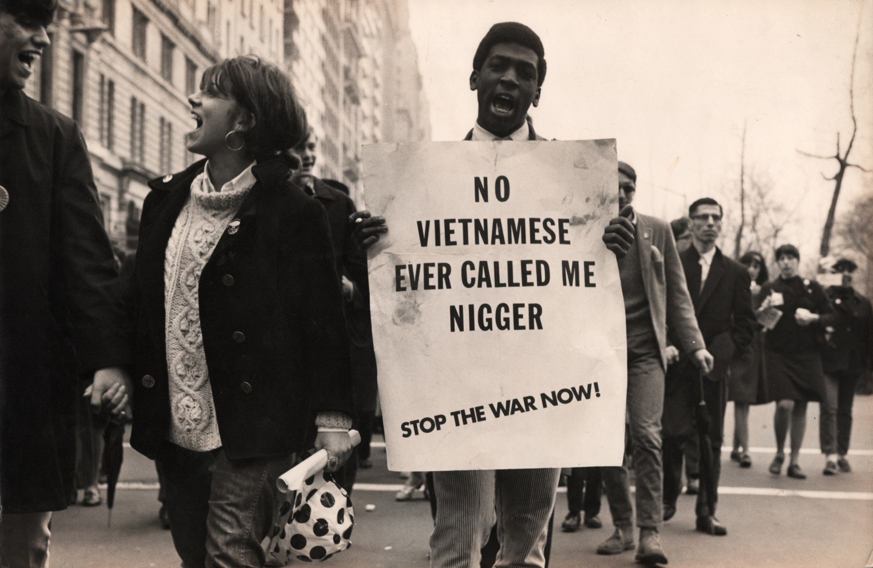 34. LeRoy Henderson, 1st Anti-Vietnam War Rally, Marchers on Madison Avenue, April 15, 1967. A young man marches in the street holding a sign that reads &quot;No Vietnamese ever called me nigger - stop the war now!&quot;