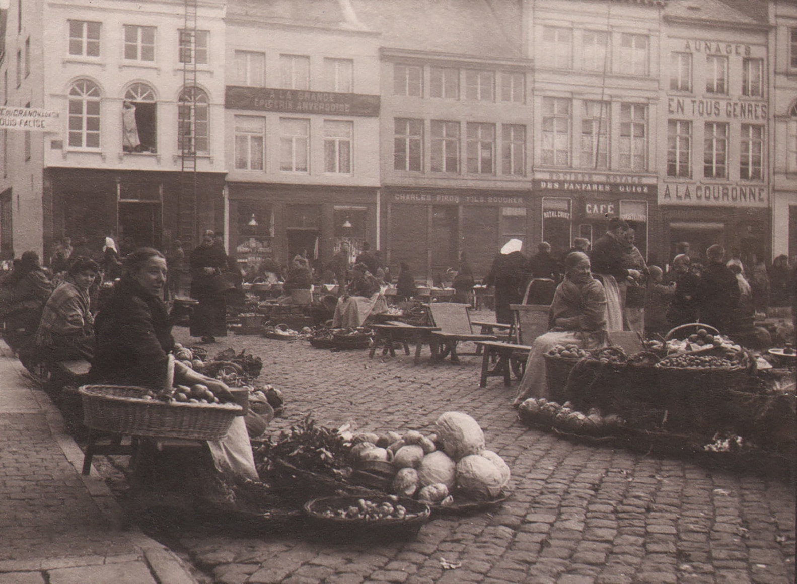 23. L&eacute;onard Misonne, Untitled, c. 1930. Market vendors on a cobbled commercial street with various forms of produce. Sepia-toned print.