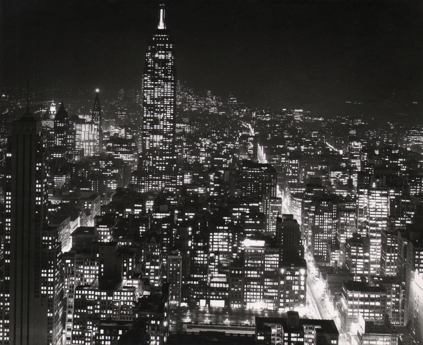 32. Sheldon Hine, New York City at Night Atop Radio City, ​c. 1938. Nighttime cityscape in a horizontal composition with the Empire State in the top left quadrant of the frame.