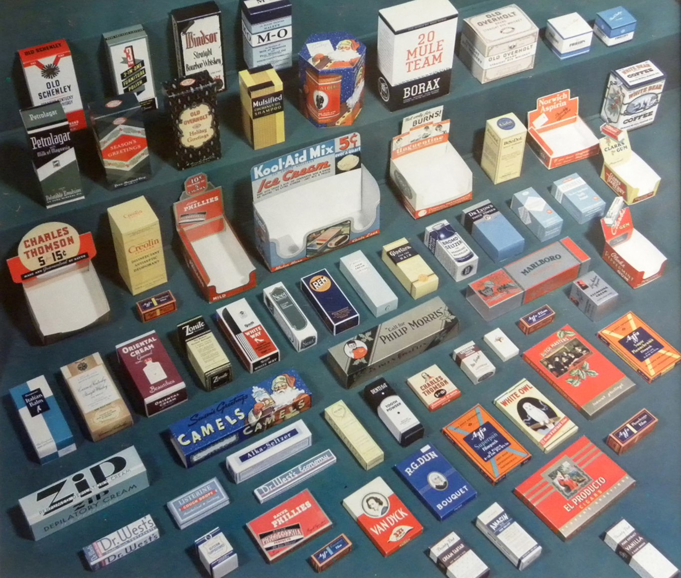 Harold Haliday Costain, Advertising Display &amp; Packaging, ​1937. Packaging for various convenience items (cigarettes, aspirin, coffee, etc.) arranged on a blue surface.