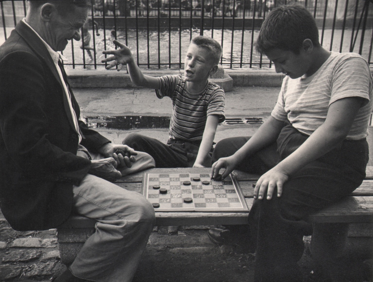14. Jeanne Ebstel, Untitled, c. 1947. A young boy and a man sit across from each other playing checkers. Another boy seated between them gestures emphatically towards the man.