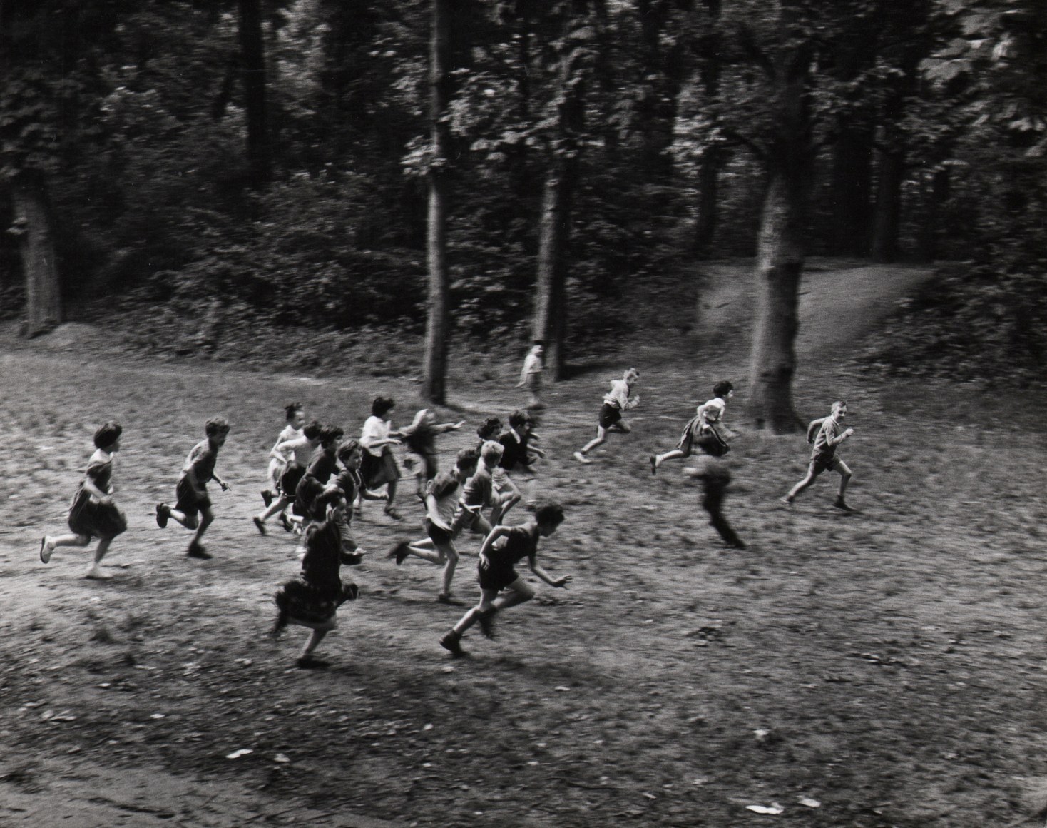 52. Janine Ni&eacute;pce, La course, c. 1960. A group of children, blurred with motion, run from left to right across the frame in a wooded setting.