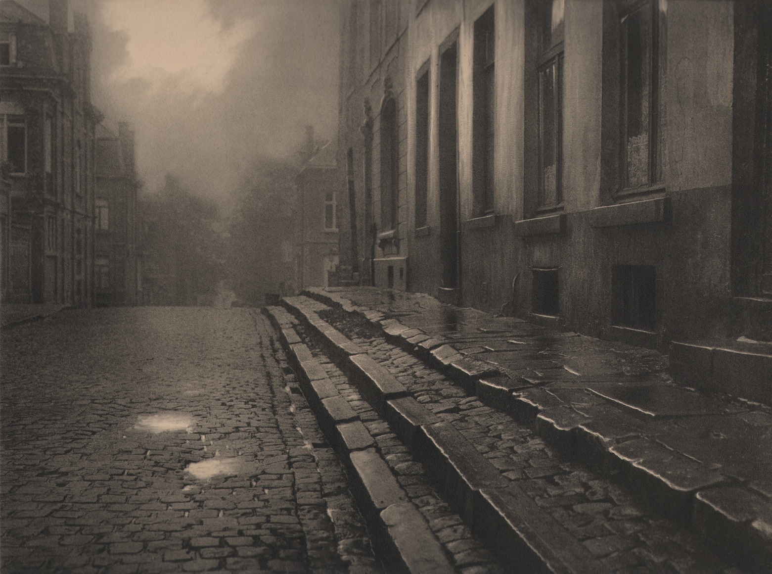 09. L&eacute;onard Misonne, [title illegible], c. 1930. Wet, cobbled, residential street and steps in soft light. Sepia-toned print.
