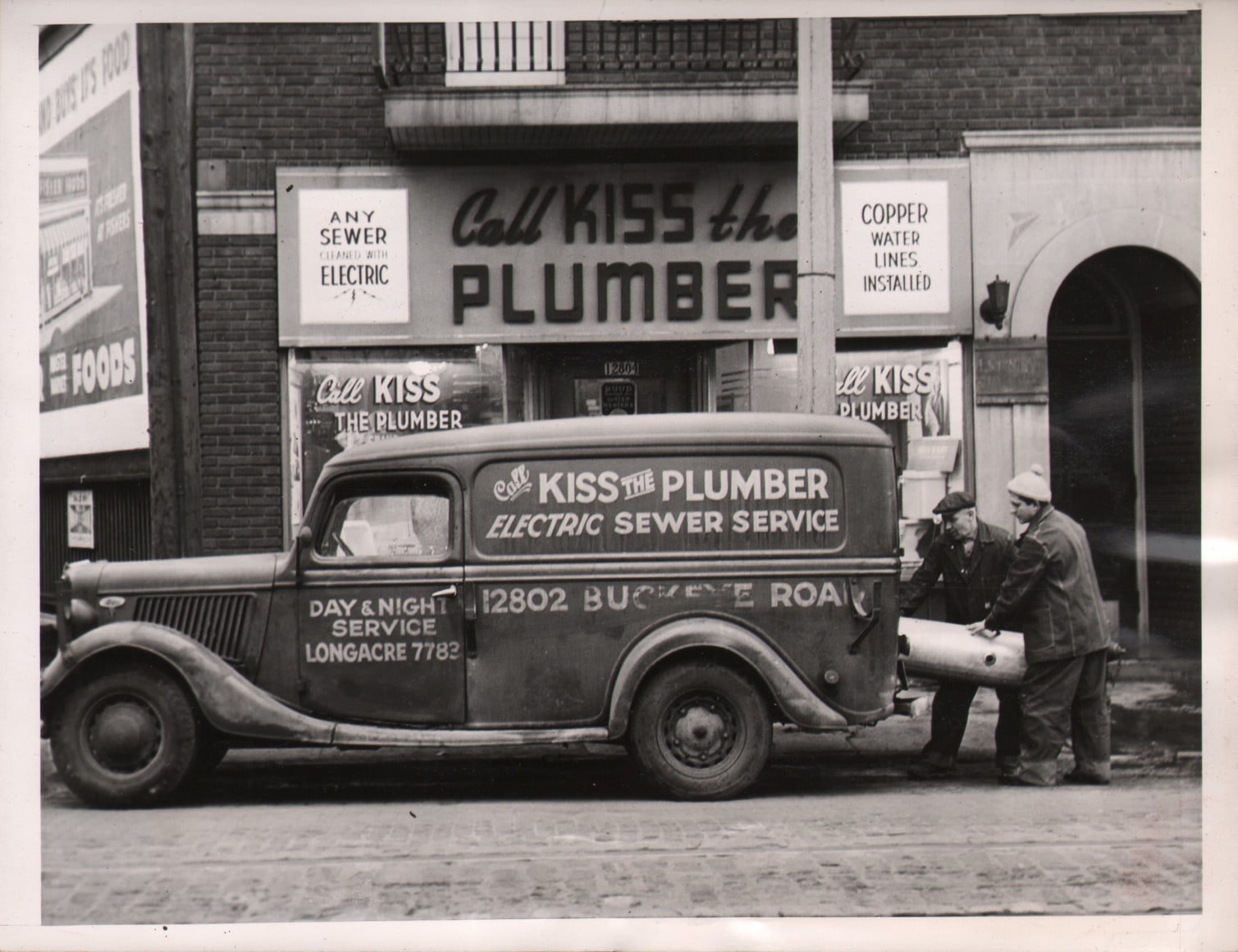 43. Acme Photo, &quot;Kiss the Plumber&quot; - A Business, Not a Pastime, February 1, 1946. Men loading a truck marked &quot;Call Kiss the Plumber Electric Sewer Services&quot; in front of a storefront with the same name.