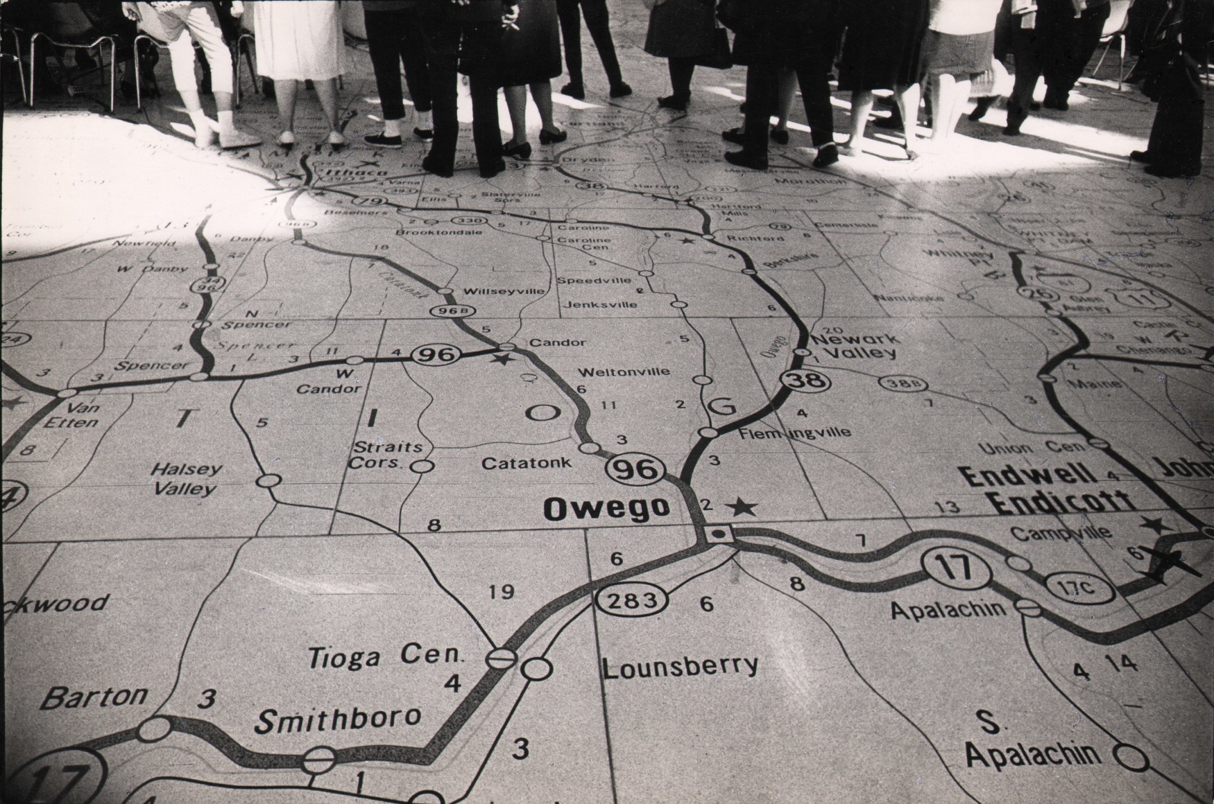 42. Jan Lukas, New York World Fair, ​1964. Looking down on a floor with a map of New York State on it. The lower bodies of figures are visible at the top of the frame.