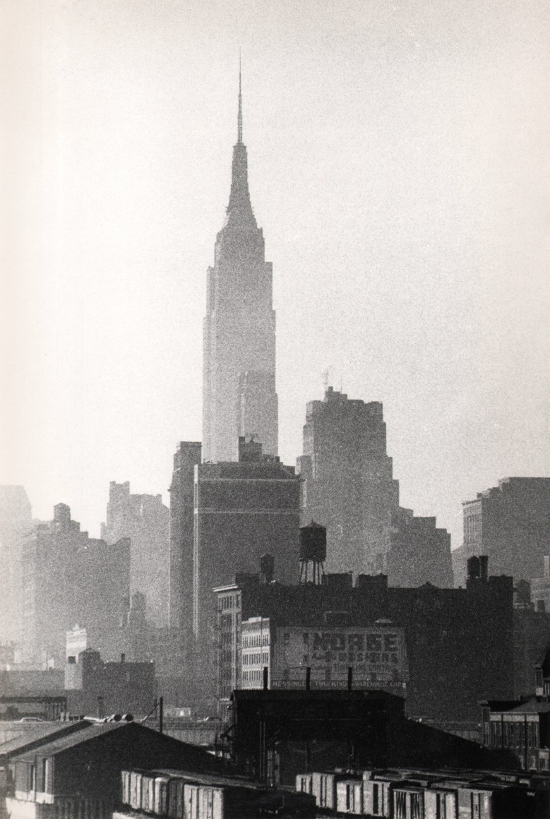36. Marvin Koner, Empire State Building, ​c. 1955. Grainy vertical composition with the Empire State at the center climbing above surrounding builidings.