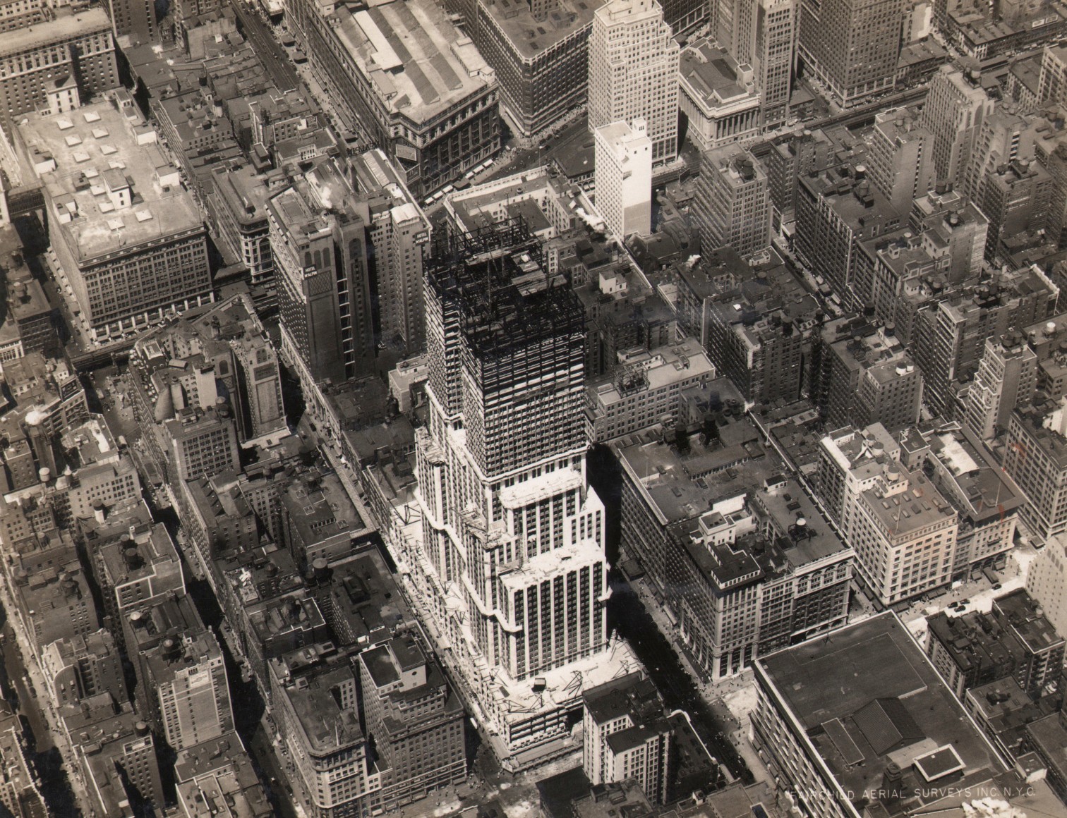 22. Fairchild Aerial Surveys, Empire State Building Construction, West 34th Street, New York City, ​1930. Aerial view of the in-progress Empire State Building, built up to about half its total height.