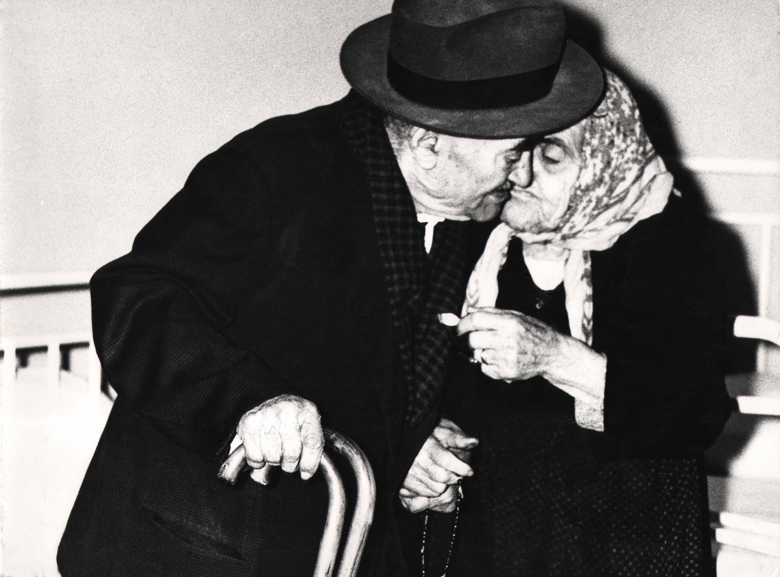 32. Mario Giacomelli, Verr&agrave; la morte e avr&agrave; i tuoi occhi, 1966&ndash;1968. High contrast image. An old couple in dark clothing kiss.