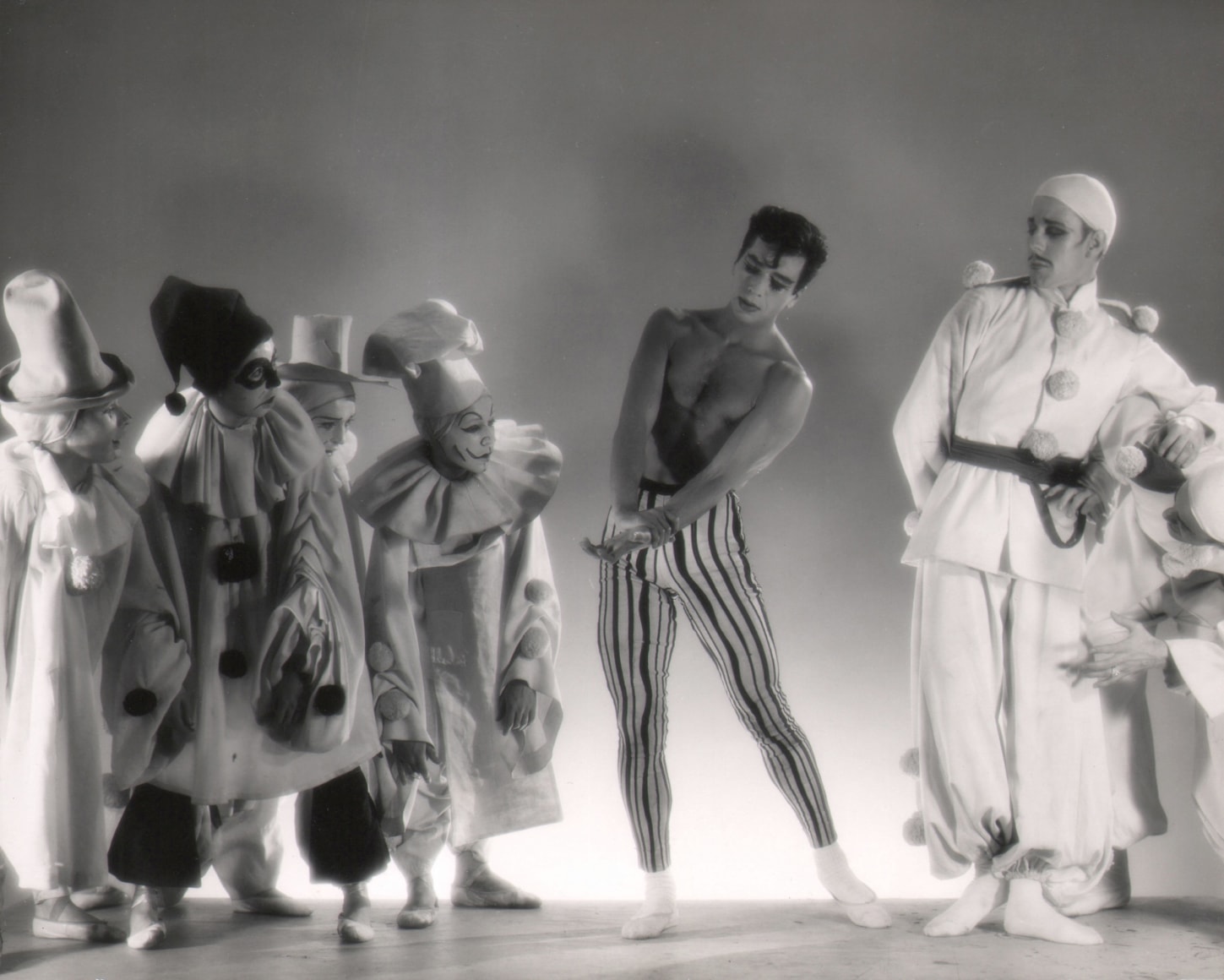 George Platt Lynes, Illumination, Nicholas Magallanes &amp; Brooks Jackson, ​c. 1950. Seven dancers pose in clown costumes. All looking to the central shirtless male figure.