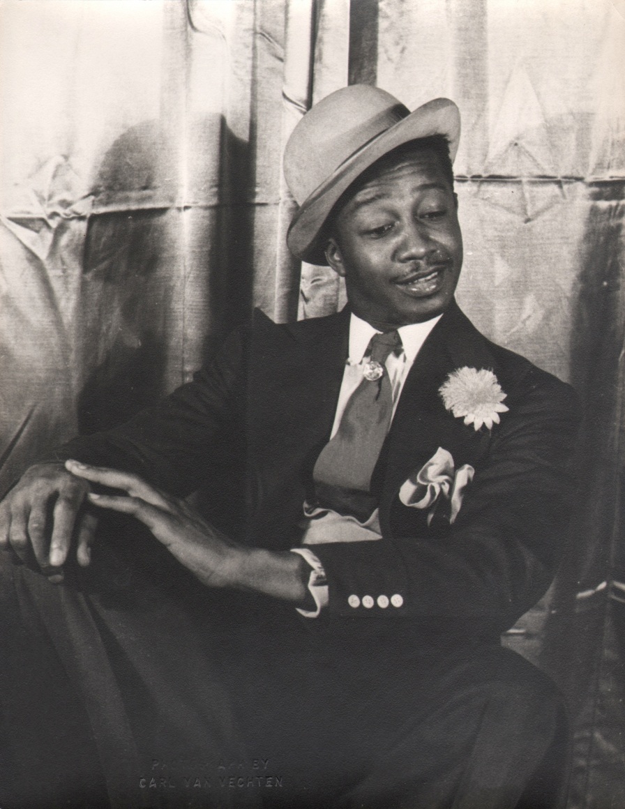 37. Carl Van Vechten, Avon Long as Sporting Life, Porgy &amp; Bess, 1942. Subject in a seated pose with legs crossed and hands on knee, looking down and to the right.