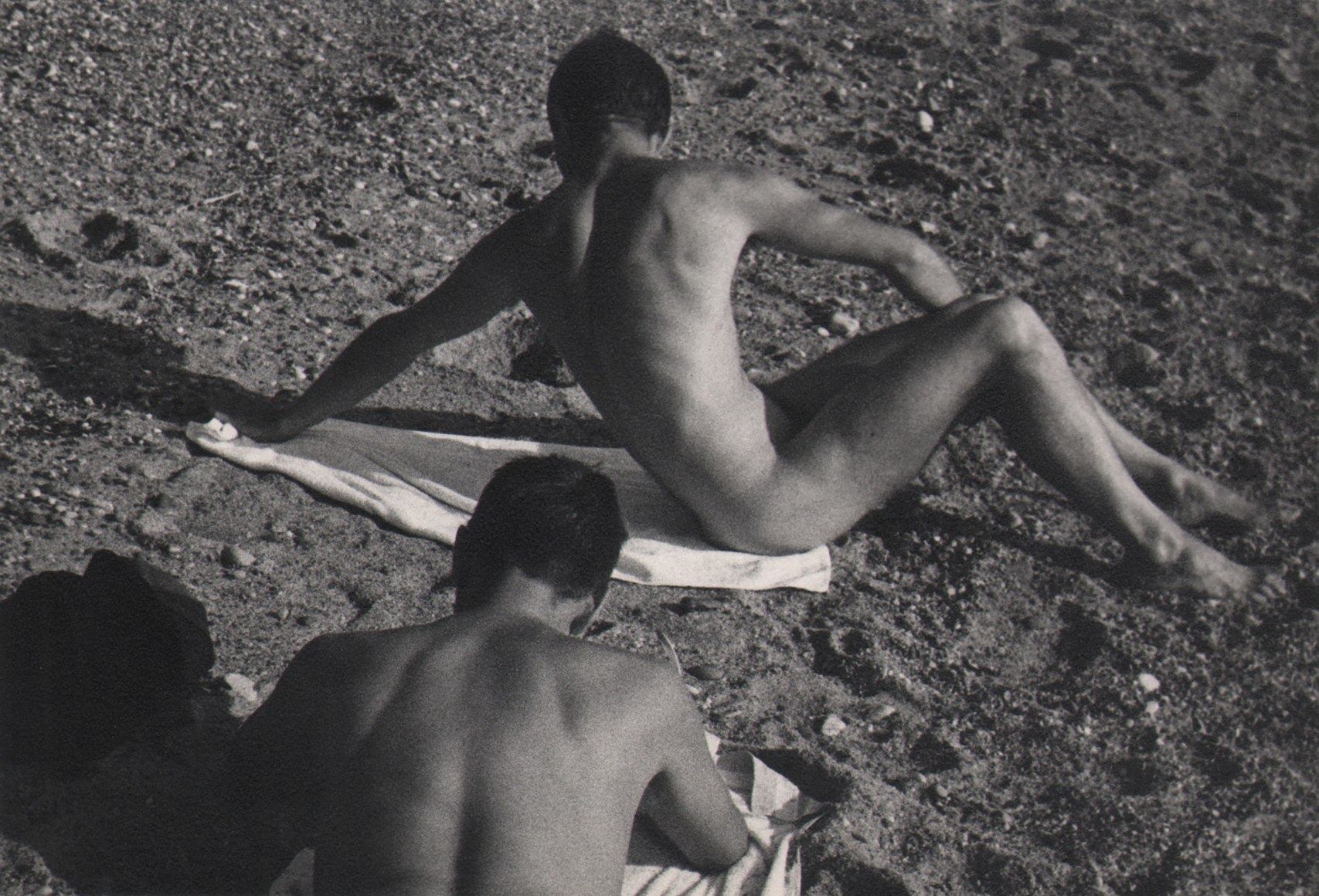 PaJaMa, George Tooker &amp; Paul Cadmus, Provincetown, ​c. 1945. Two male nude figures on towels on the beach, backs to the camera. One lays on his stomach, the other sits, leaning back on one hand.