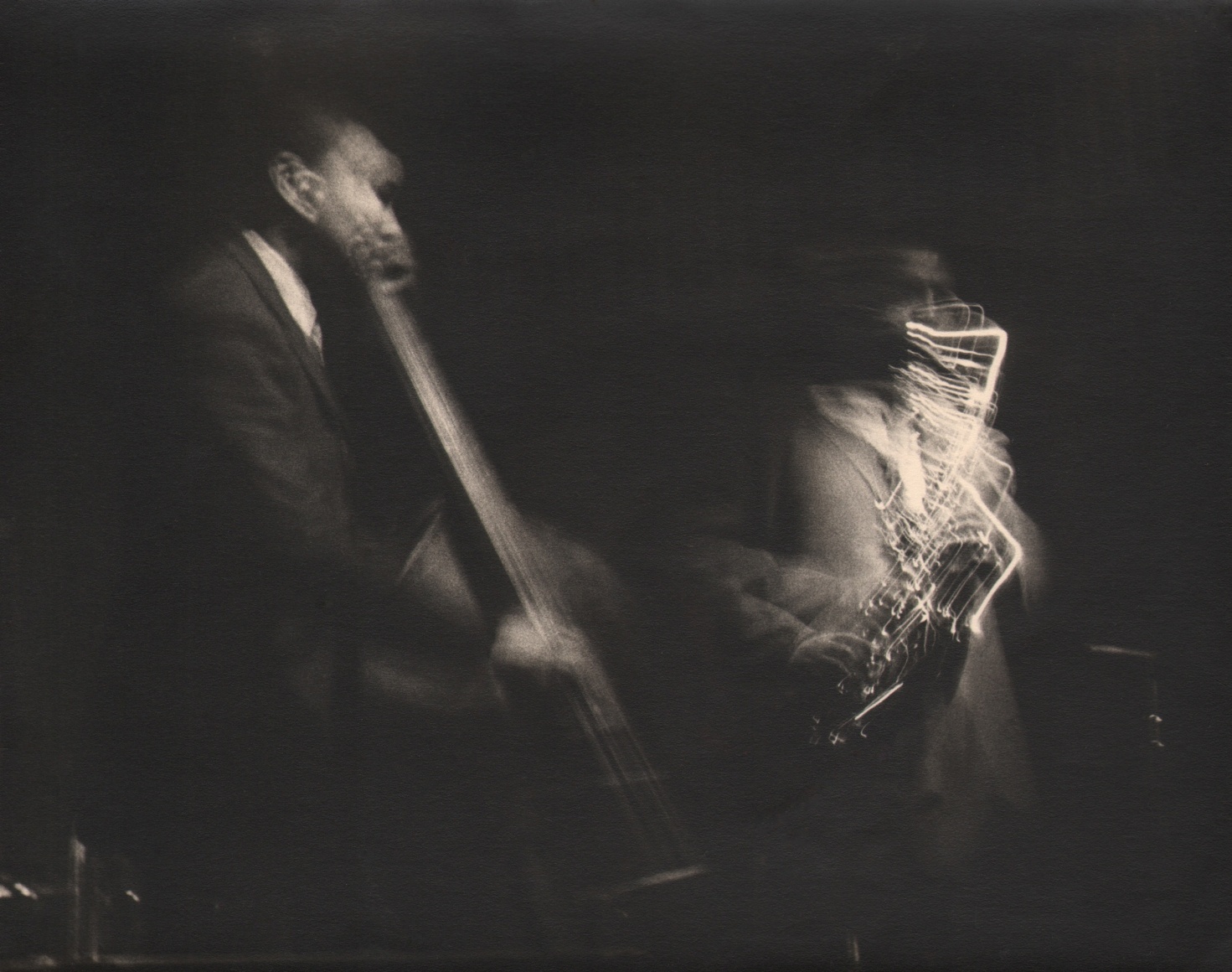 38. Beuford Smith, Paul Chambers, John Coltrane, ​c. 1970. Dark exposure of two figures blurred with motion, playing instruments.