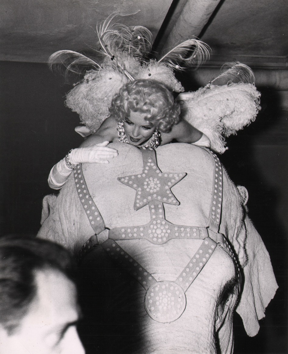 24. Weegee, Marilyn at the Circus, ​c. 1955. Marilyn Monroe in a feathered costume riding on the back of an elephant.