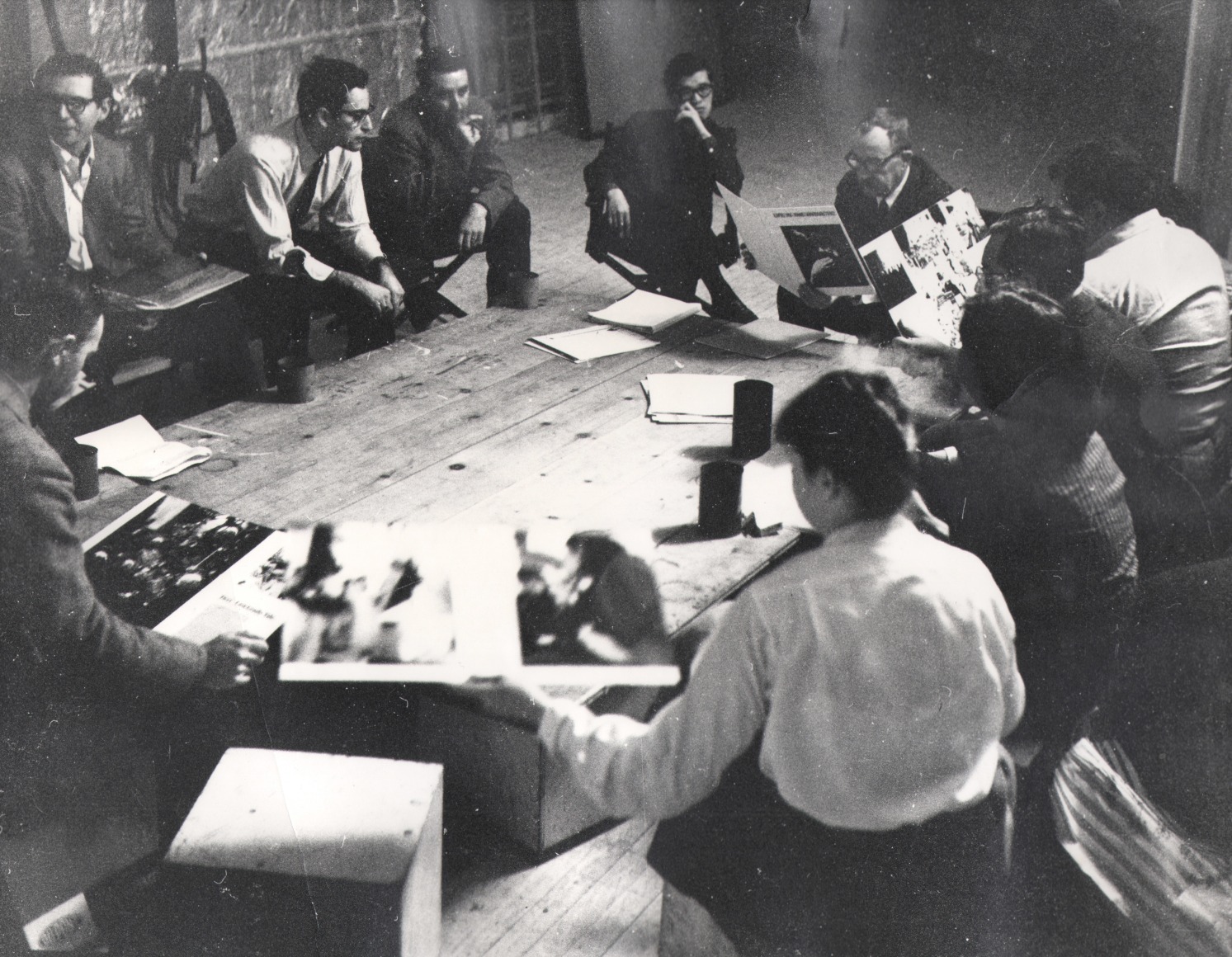 03. David Attie, Brodovitch Design Laboratory, Richard Avedon's Studio, c. 1957. A group of at least ten people sit in a circle on a wooden floor, reviewing prints.