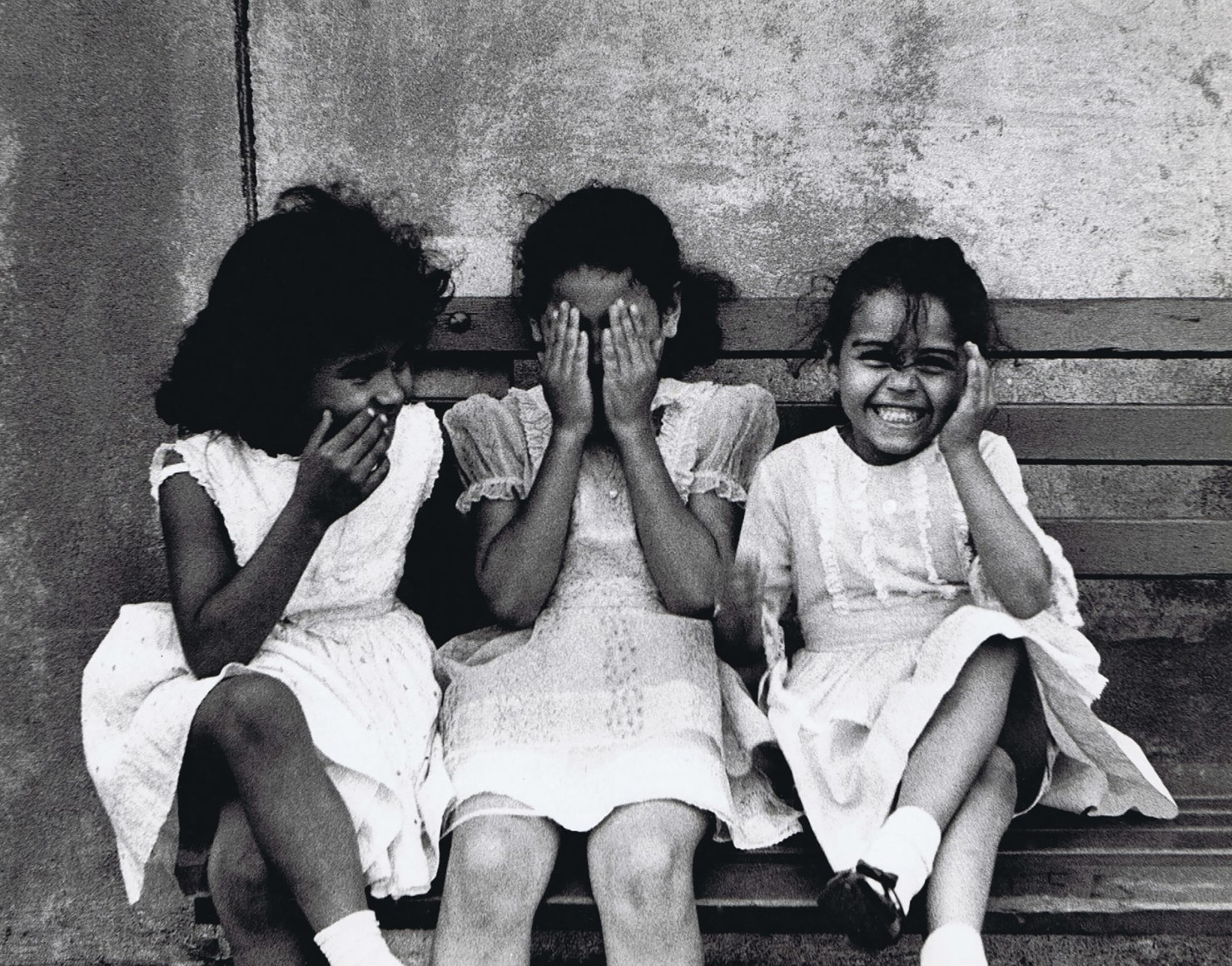 28. Beuford Smith, Three Girls, Bronx, ​1968. Three young girls in white sitting on a bench. One covers her mouth, one her eyes, the last covers on ear.