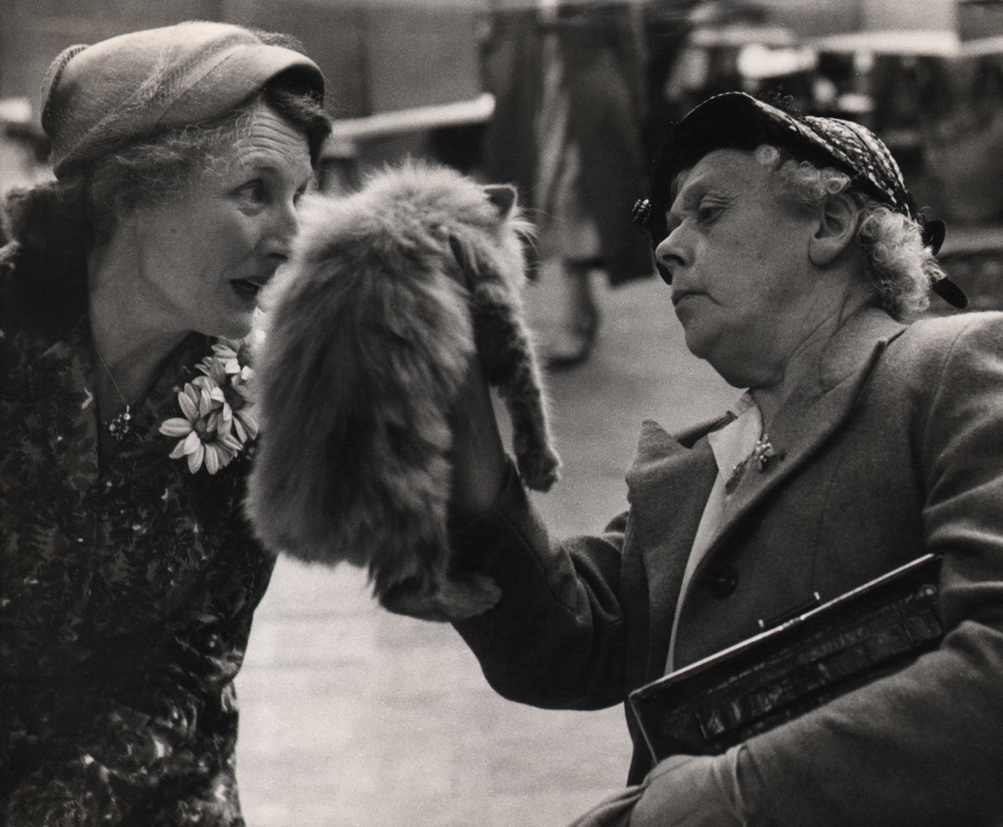 22. Grace Robertson, Cat Fanciers, ​c. 1956. Two middle-aged people examining a cat, which is held up in front of the figure on the right using their right hand.