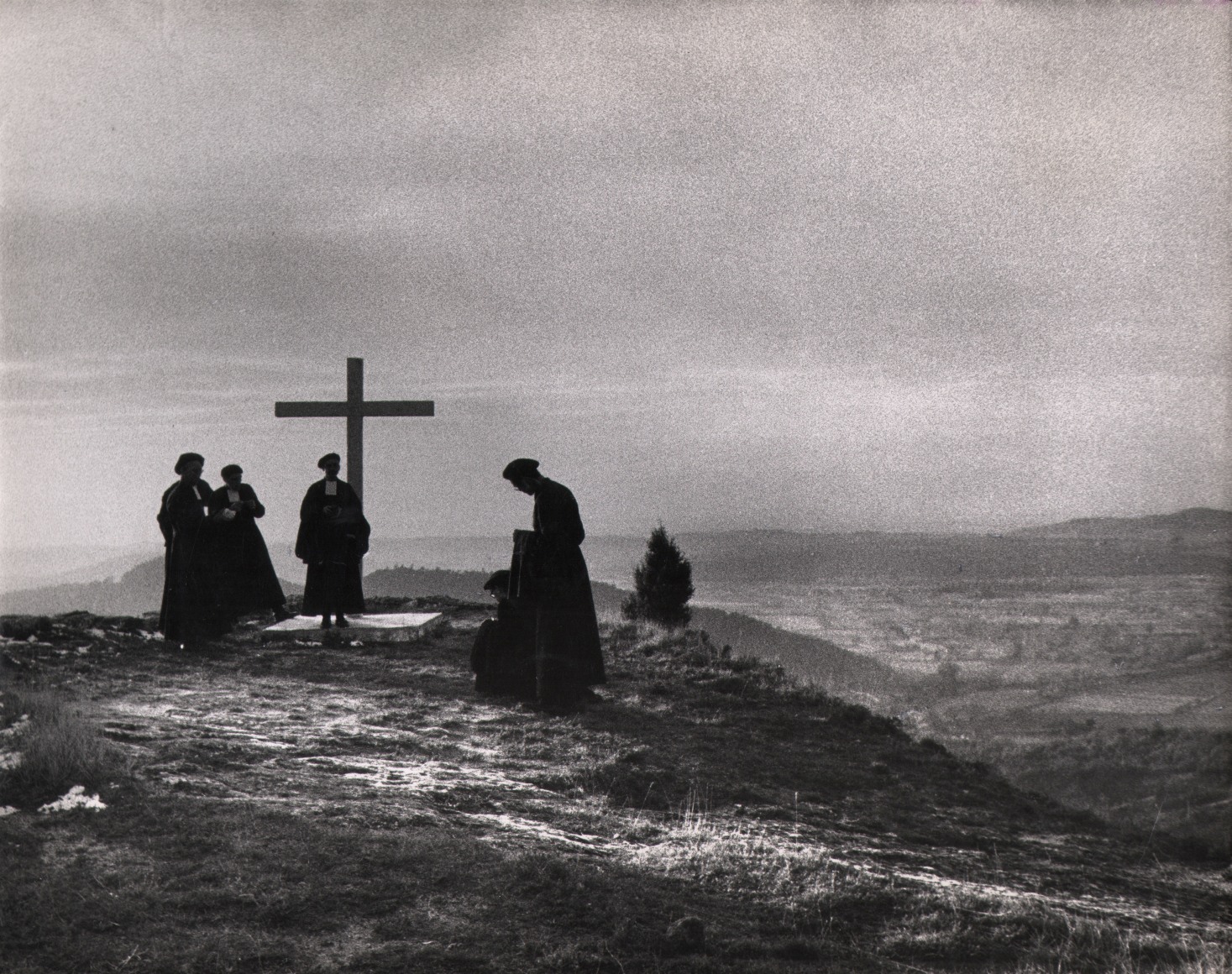 41. Sabine Weiss, France, 1956. Silhouetted, robed figures on a mountaintop with a cross.