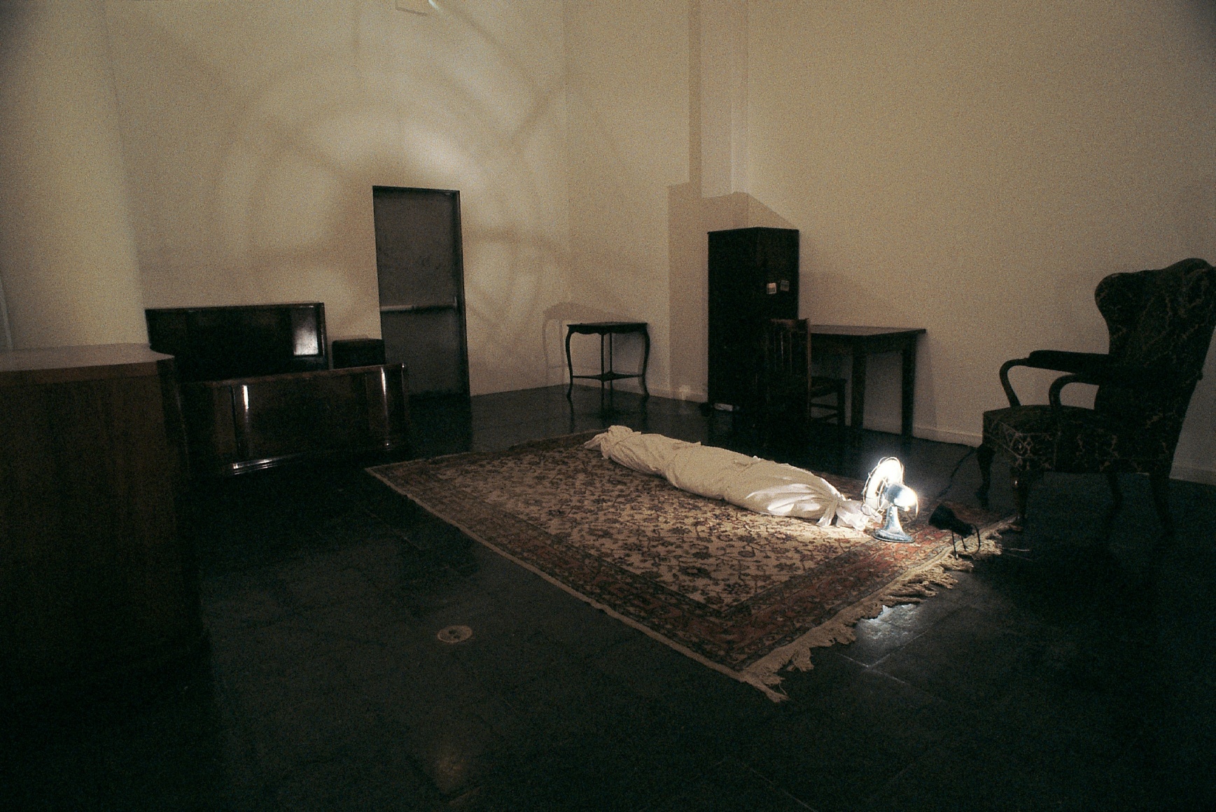 Hale Tenger, Shroud, 1996, Found furniture, carpet, fan, spotlight, toddler shoes and photographs, and shroud