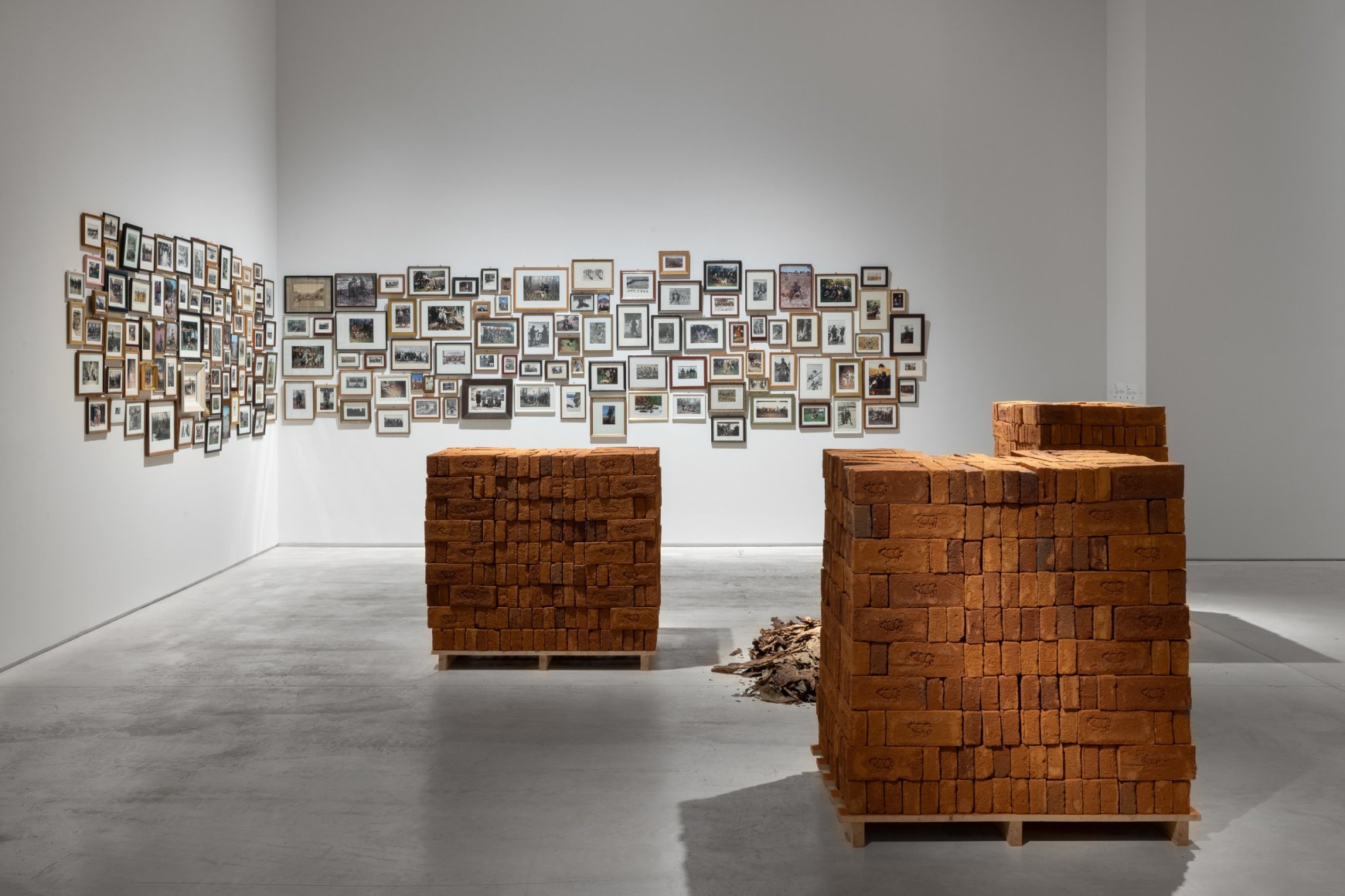 Rossella Biscotti, Clara, 2016, 3 pallets of handmade bricks, tobacco and vinyl wall text, Dimensions variable
