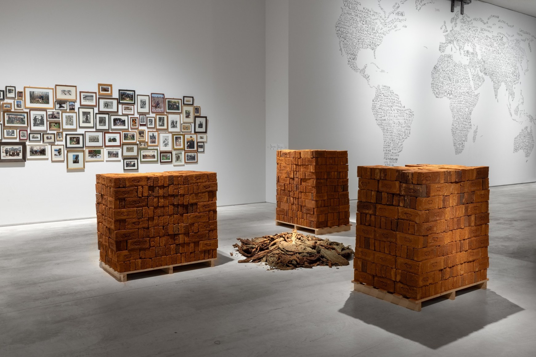 Rossella Biscotti, Clara, 2016, 3 pallets of handmade bricks, tobacco and vinyl wall text, Dimensions variable