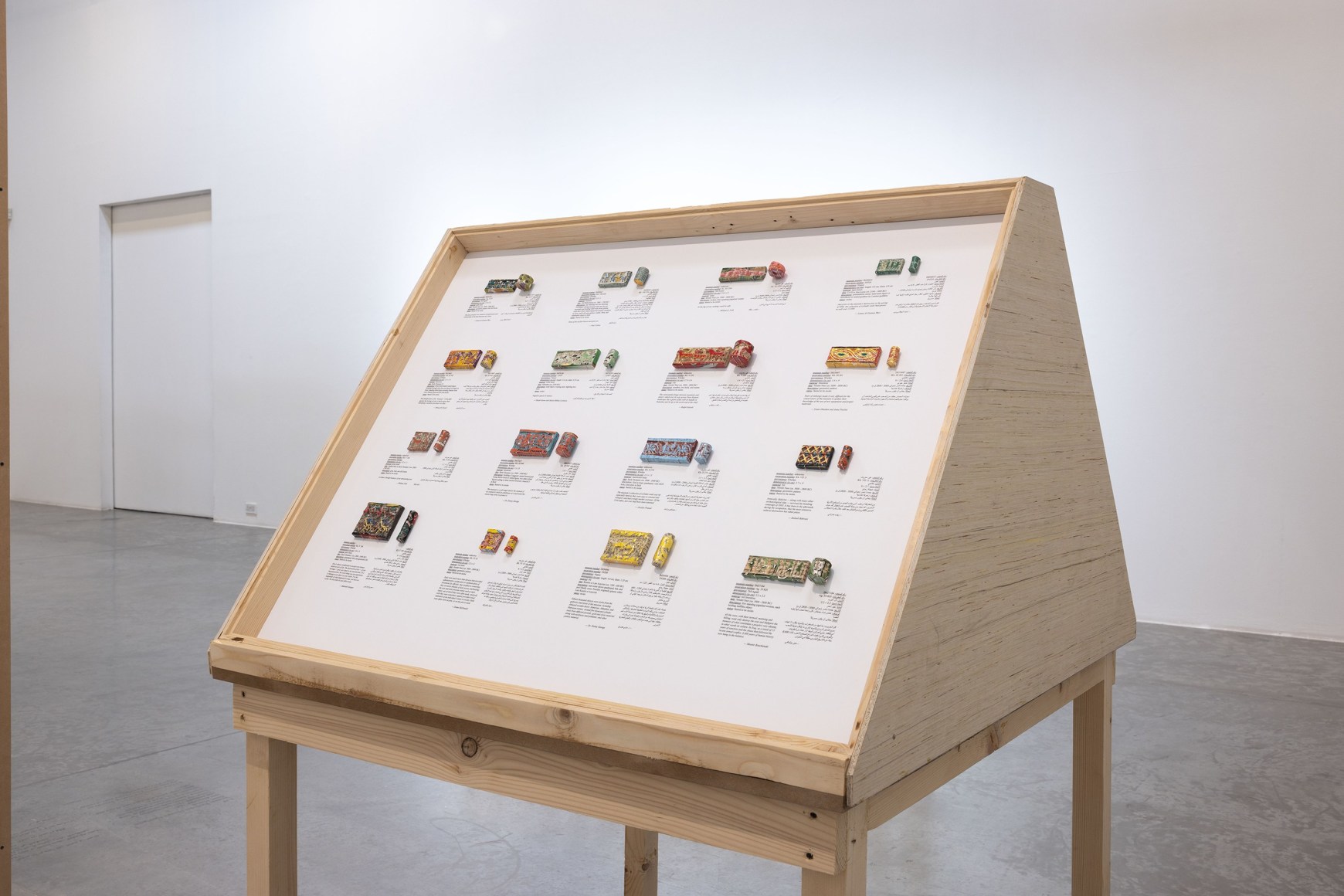 Michael Rakowitz, The invisible enemy should not exist (cylinder seals), 2022, Arabic newspaper and food packaging cardboard sculptures, museum labels