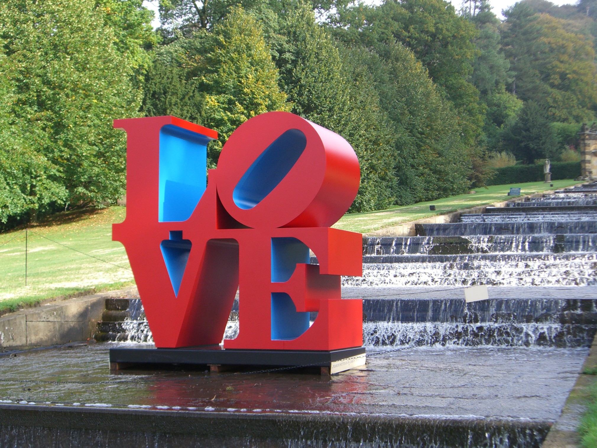 A 96 by 96 by 48 inch polychrome aluminum sculpture spelling love, consisting the letters L and a tilted letter O on top of the letters V and E. The outsides of the letters are the color red, and the insides are blue.