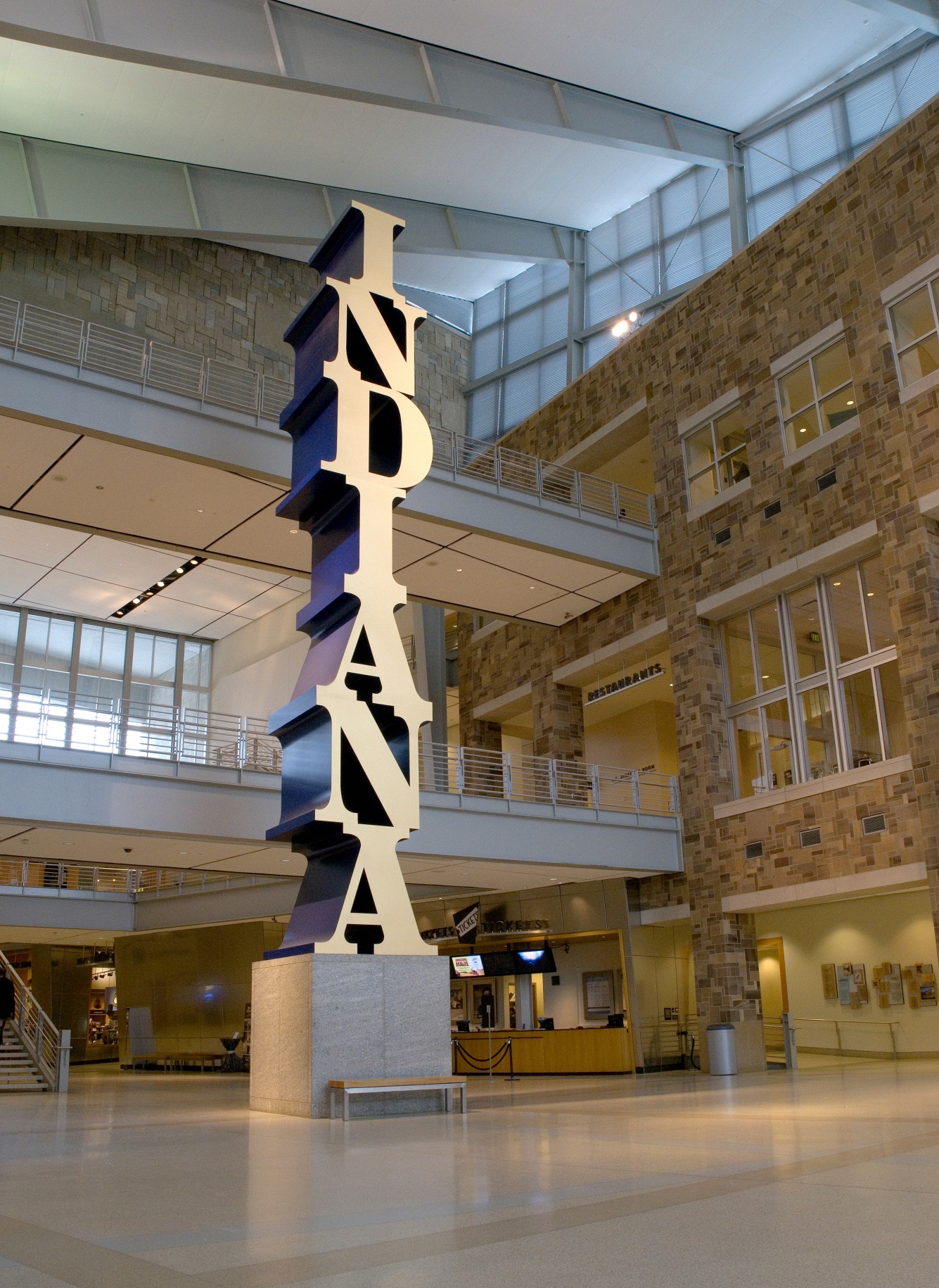 The Indiana Obelisk is a 575 1/4 inch high, with base, polychrome aluminum sculpture spelling the word Indiana vertically, starting with the I on top and ending with the A on the bottom. The letters have gold faces and blue sides.
