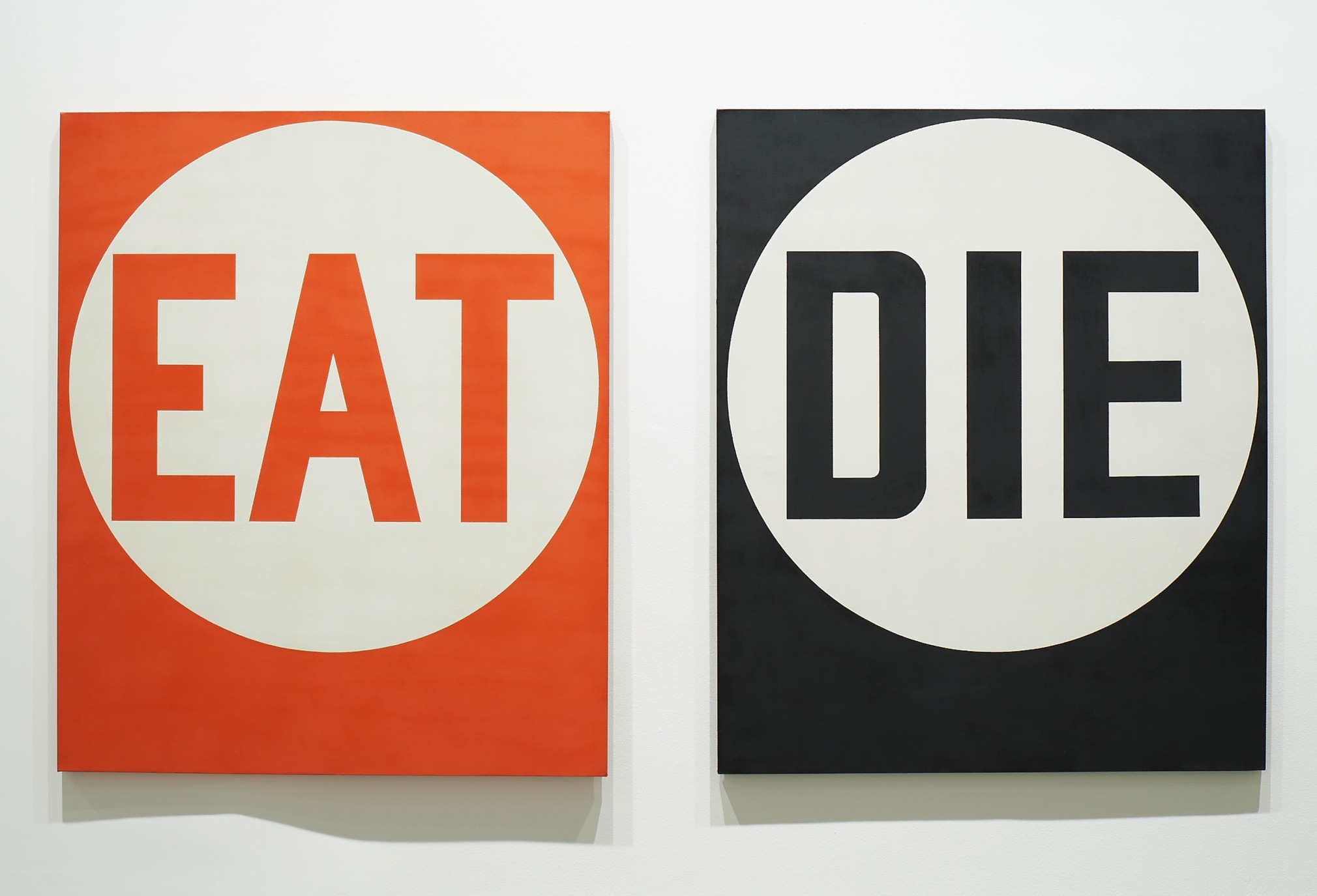 A diptych; one panel contains the word Eat in red letters within a white circle against a red background. The second panel consists of the word Die in black letters within a white circle against a black background.