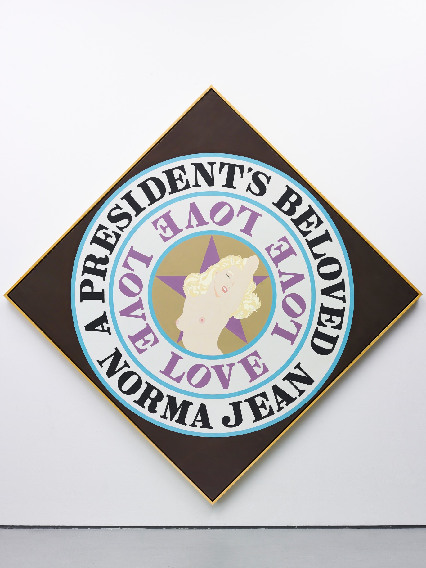 A President's Beloved is a 101 3/4 by 101 3/4 inch diamond shaped canvas with a black ground. A light brown circle surrounded by two white concentric rings with blue outlines dominates the canvas. In the center is an image of a topless Monroe against a purple star. The first ring contains the word Love painted in purple four times. The outer ring contains the text &quot;A President's Beloved Norma Jean&quot; painted in black.
