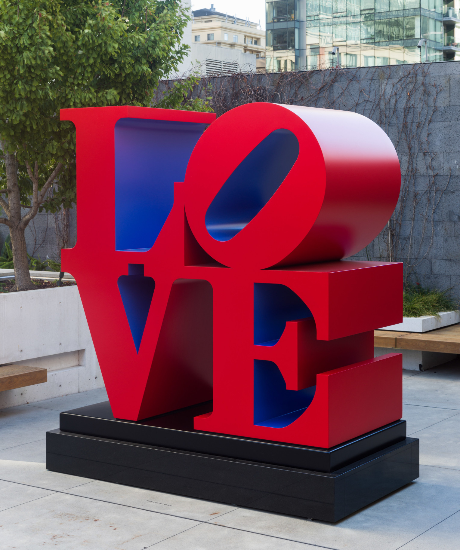 A 96 by 96 by 48 inch polychrome aluminum sculpture spelling love, consisting the letters L and a tilted letter O on top of the letters V and E. The outsides of the letters are red, and the insides are violet.