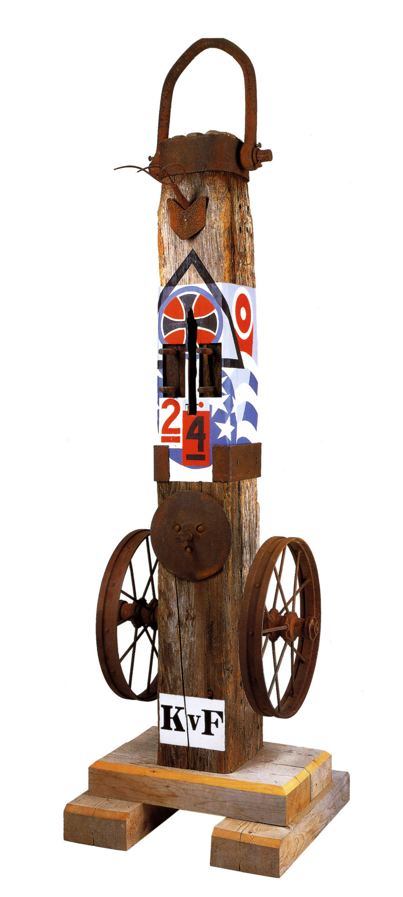 A 138 by 38 1/2 by 45 inch sculpture consisting of a wooden beam on a wooden base. The work's title, &quot;KvF&quot; appears in stenciled letters against a white ground. An iron wheel is affixed to the right and left sides of the sculpture. On the front of the sculpture, level with the top of the wheels, is an iron disk. Above this a section of the sculpture has been painted with red, blue, white, and black designs that include a cross, stars, and the numbers 2 and 4. At the top of the sculpture is an iron cap with a handle.