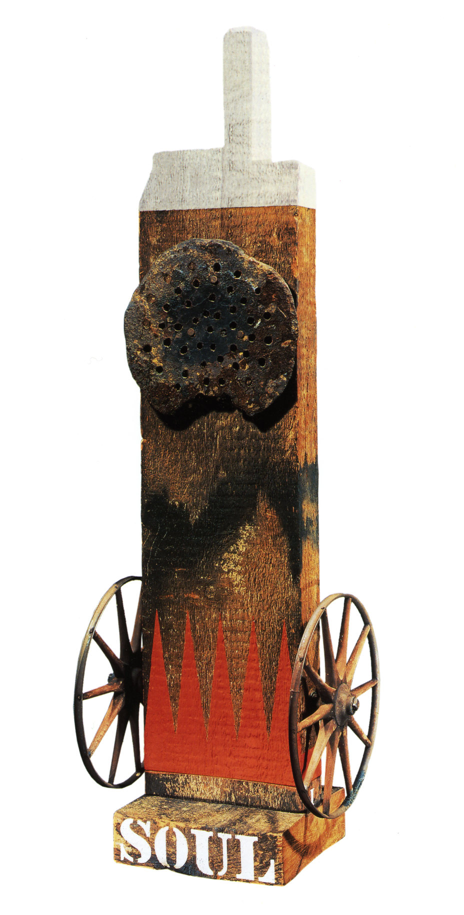 A 50 1/2 by 16 3/4 by 13 1/2 inch sculpture consisting of a wooden beam with a tenon, resting on a wooden base. The work's title, Soul, is painted in white stenciled letters across the bottom of the base. Iron wheels have been affixed to the bottom left and right of the sculpture, in between the wheels are red painted flames. Towards the top of the sculpture is a weathered metal disk. The beam's tenon and top few inches have been painted white.