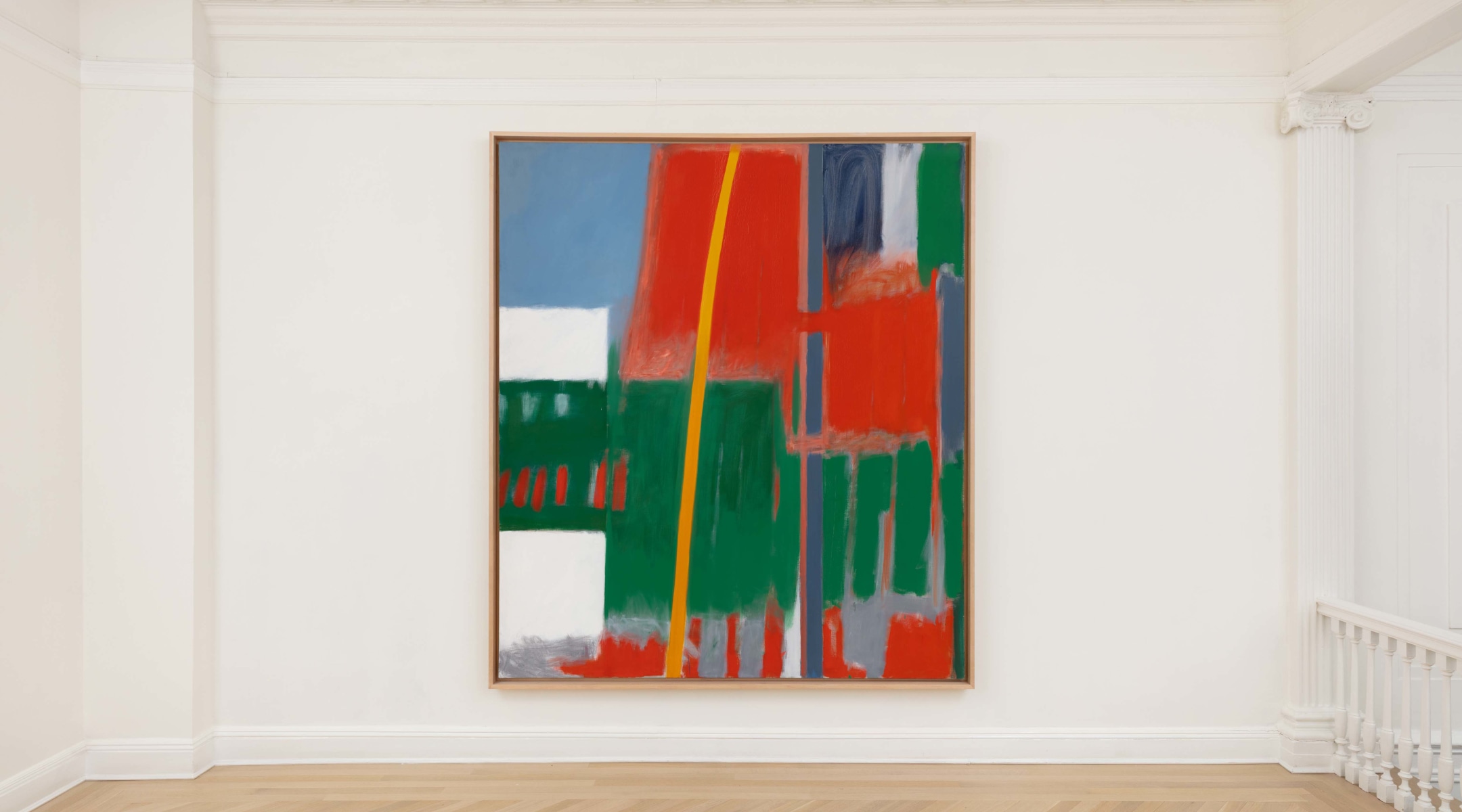 Abstract painting with red green blue yellow and white hanging in gallery lobby