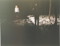 Man standing behind woman in forest at night, photo