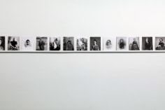 black and white postcards of women on shelf on gallery wall