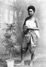 Black and white postcard of woman standing next to growing plant