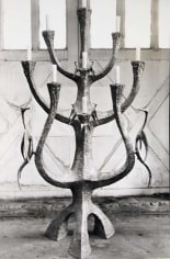 Black and white image of a decorative menorah with candles. The menorah is sculptural and unique, with bird motifs on the sides.