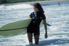 Slim Aarons, Minnie Cushing, September 1965: American society girl Minnie Cushing carries her surfboard under her arm
