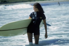 Slim Aarons, Minnie Cushing, 1965: American society girl Minnie Cushing carries her surfboard under her arm