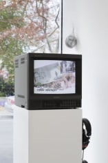 A video monitor installed on a pedestal with headphones against a window.