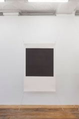 A photograph of one screenprint, stretched at all 4 corners. The center is black and the framed around it is white. The work resembles a polaroid in it's arrangement.