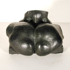 Black colored sculpture of a two oval shapes forming a heart next to each other resembling a human buttocks. 