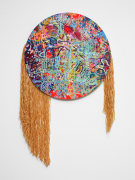 A multicolored painting on a circular canvas. The work is abstract with talismans and shapes resembling vegetation throughout. Raffia straw is attached and hangs off the left and right lower sections of the canvas.