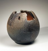 Round dark vessel with textured surface and carved irregular mouth