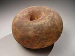Round sculpture with concave center and rough texture of deep red and black slip glaze, 2007