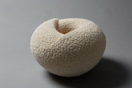 Fuka; Hatching Swirling, round white sculpture with concave center and covered both inside and outside with tiny gathered bundles of shaved clay