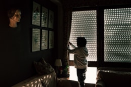 Ana Maria Jeremias opening the window in the home of an elderly lady she cares for in the Estrela neighborhood. Lisbon, Portugal, 2024