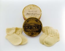 Cardboard box with two pairs of knit baby socks, worn by Rebecca Janey Merrefield's twin sons, born on May 16, 1849.